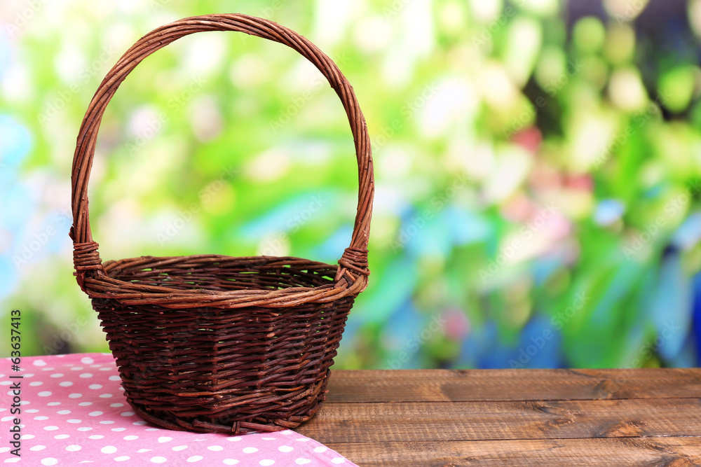 Empty wicker basket on wooden table, on bright background Empty wicker basket on wooden table, on bright background