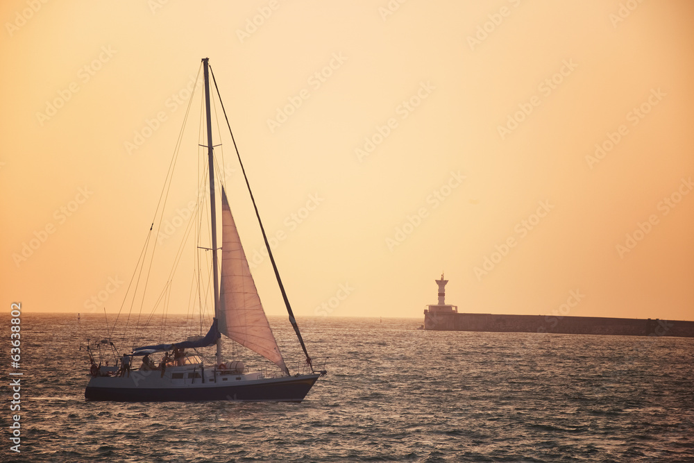 Sail boat against sea sunset