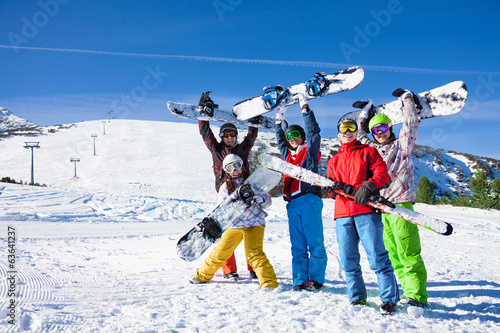 Five snowboarders holding oards and skies together
