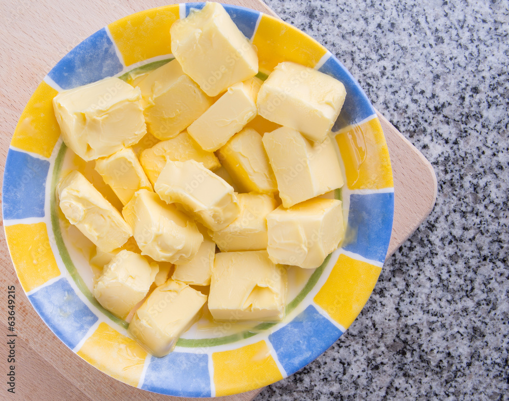 A group of melting butter in a bowl over granite surface A group of melting butter in a bowl over granite surface