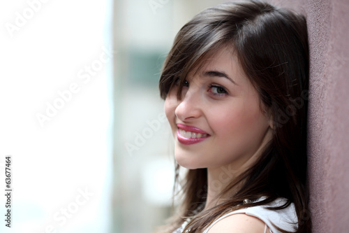 Ragazza sorridente appoggiata al muro photo