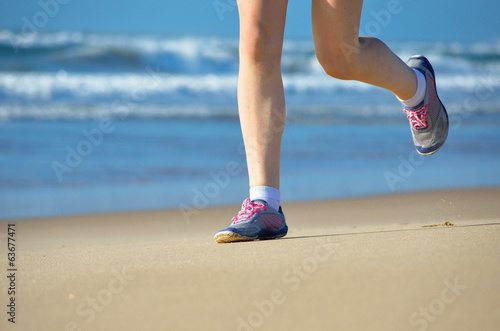 Woman runner legs in shoes on beach, running concept