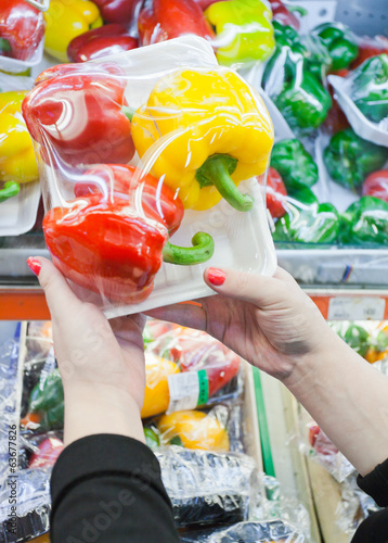Packaged bell pepper with woman hand in the supermarket