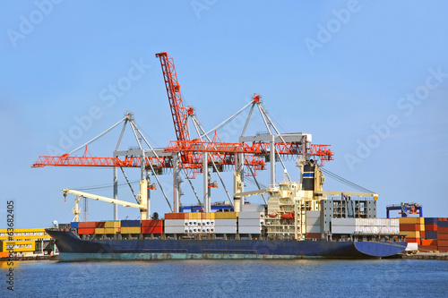 Container stack and ship under crane bridge