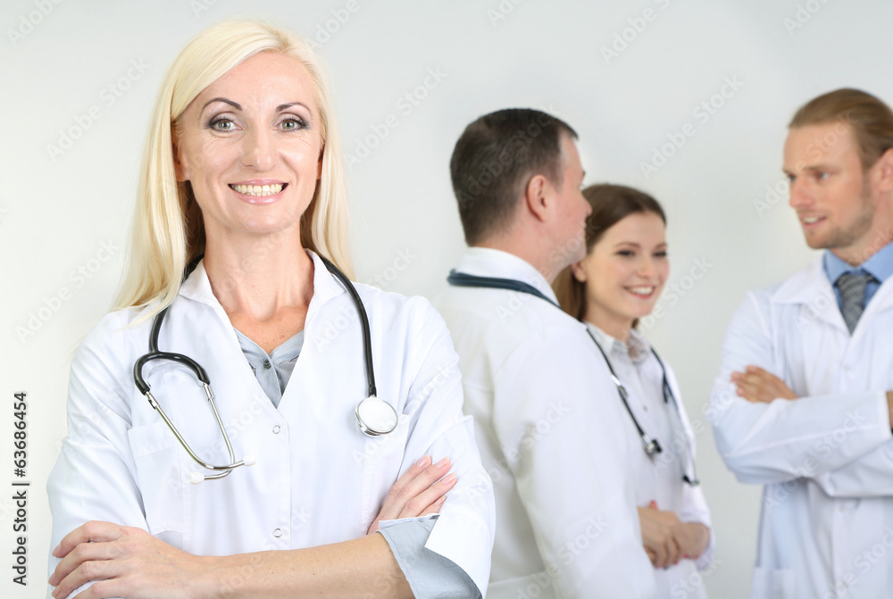 Doctor standing in front of coworkers on grey background Doctor standing in front of coworkers on grey background