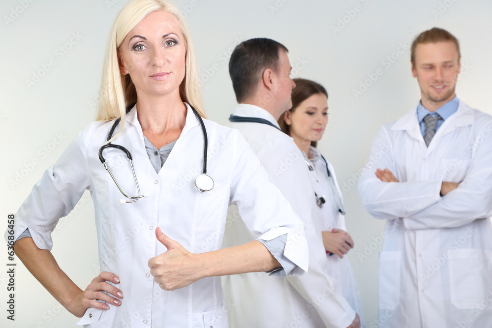 Doctor standing in front of coworkers on grey background Doctor standing in front of coworkers on grey background