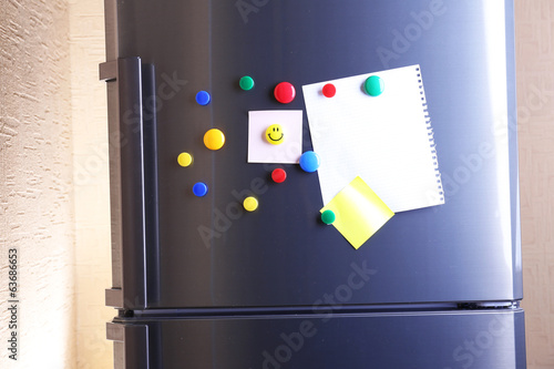 Empty paper sheets and colorful magnets on fridge door