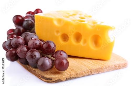 Piece of cheese and grape on wooden board, isolated on white