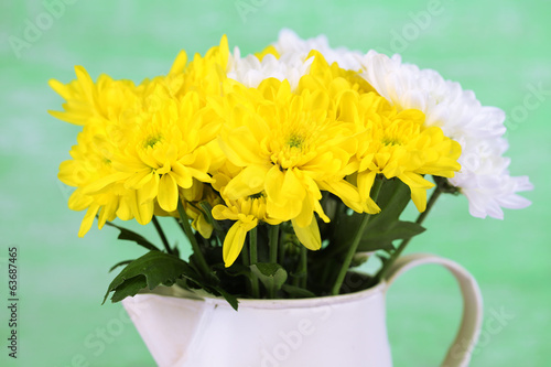 Beautiful chrysanthemum flowers in pitcher on wooden background