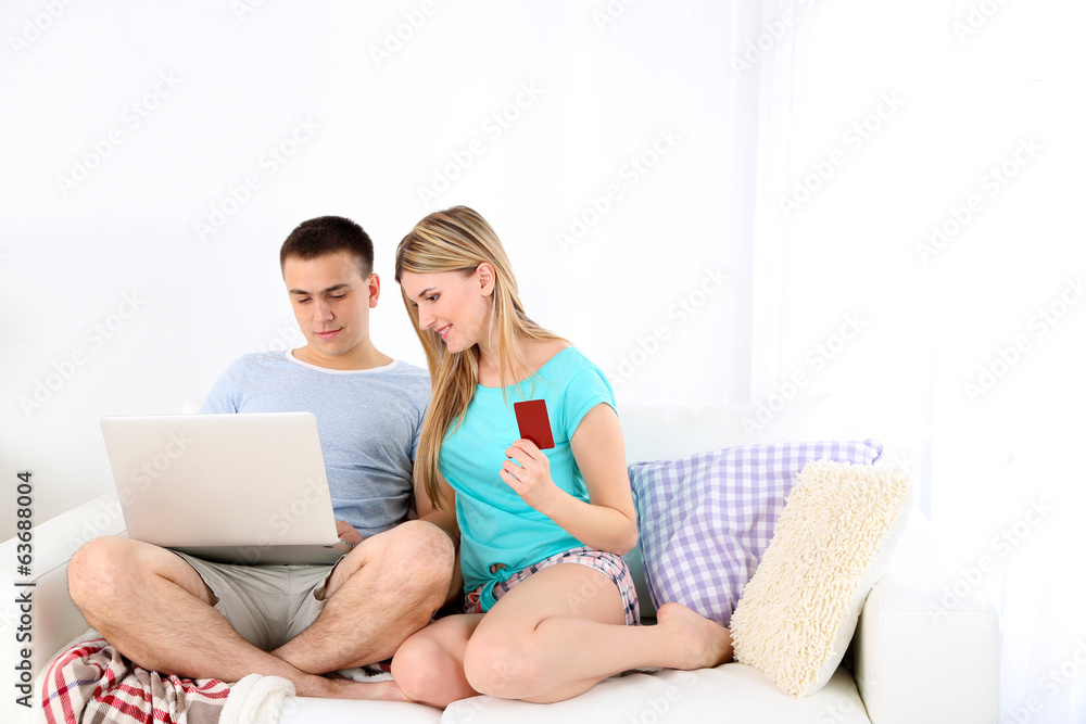 Loving couple sitting with laptop and credit card