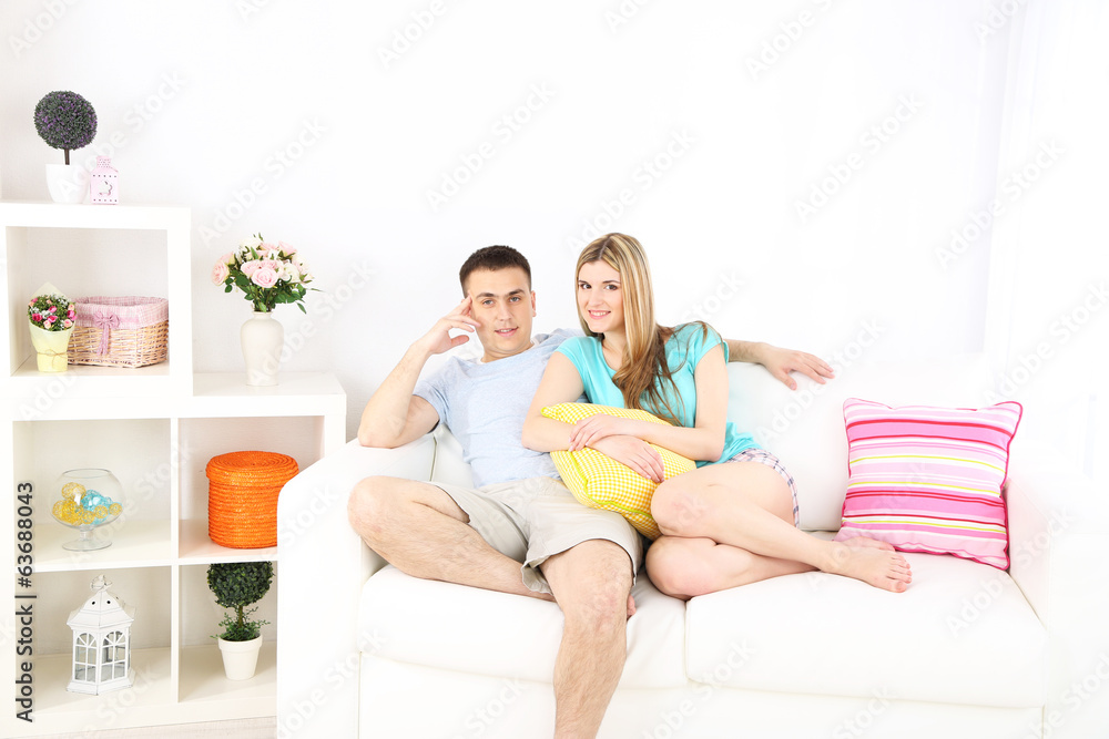 Loving couple sitting on sofa, on home interior background