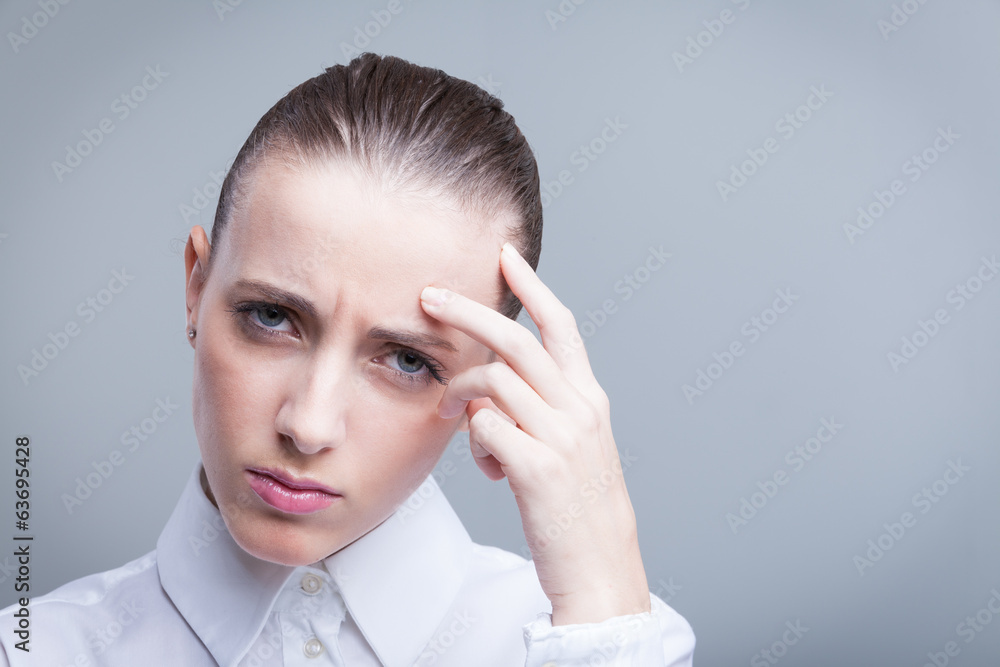 Woman having a headache holding her forehead in pain Woman having a headache holding her forehead in pain