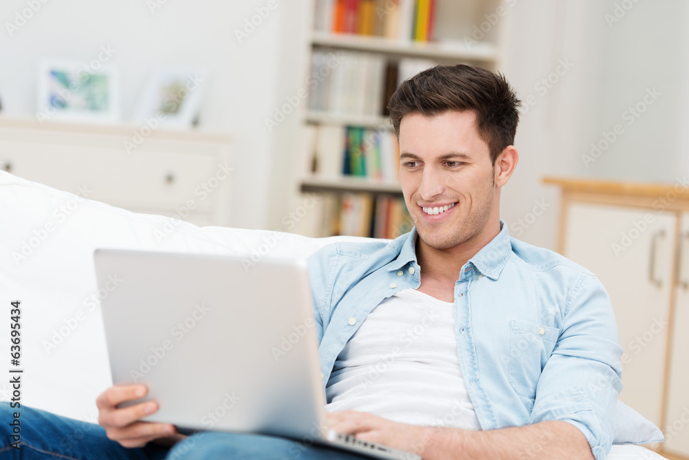 junger mann mit laptop auf dem sofa junger mann mit laptop auf dem sofa