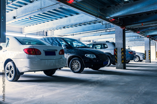 Parking garage, interior with a few parked cars.