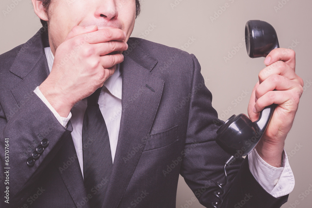 Naklejka premium Businessman on phone covering his mouth