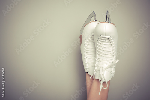 Woman wearing ice skates against a wall