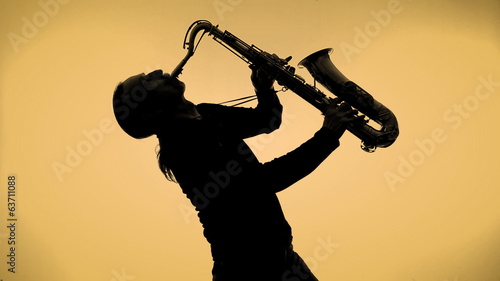Young man playing sax in the dark
