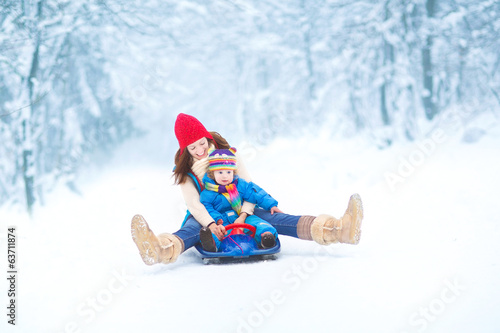 Canvas Print Young mother and her little toddler daughter enjoying a sledge