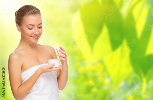 Healthy woman with bady cream on spring background photo