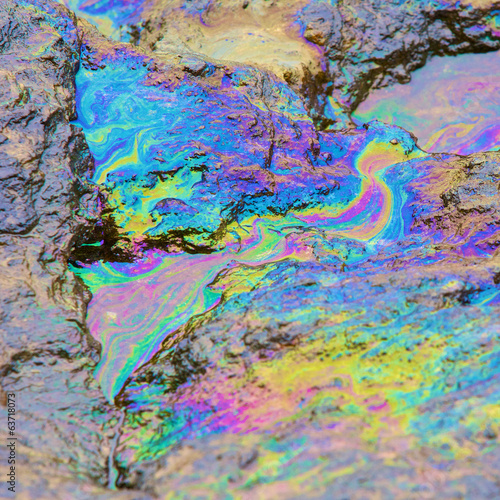 rainbow reflection of crude oil spill on the stone at the beach