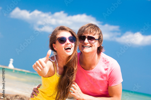 Front view of happy young couple on beach smiling and hugging.