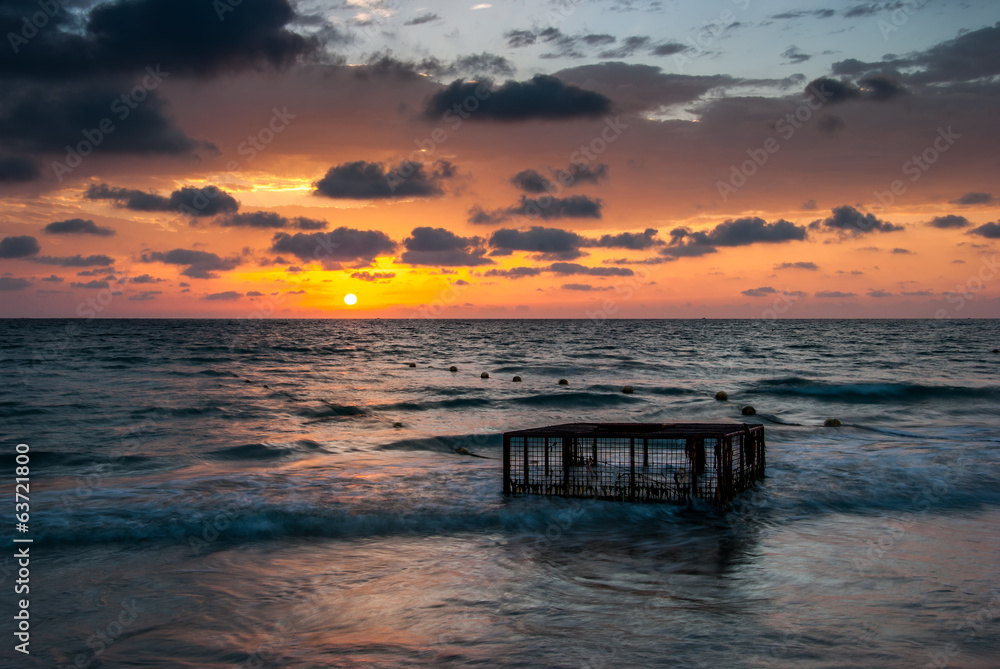 Tropical Beach with Empty Cage in the Sea at Sunset