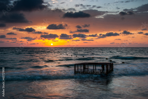 Tropical Beach with Empty Cage in the Sea at Sunset