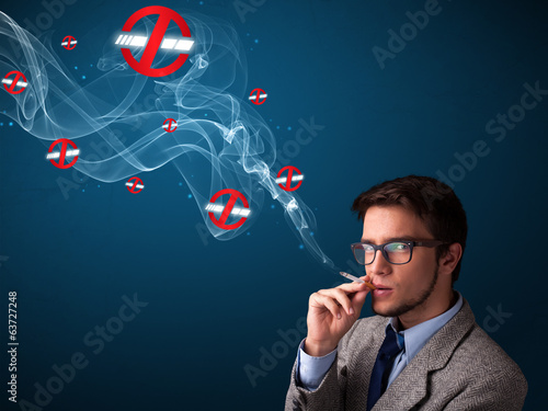 Attractive man smoking dangerous cigarette with no smoking signs