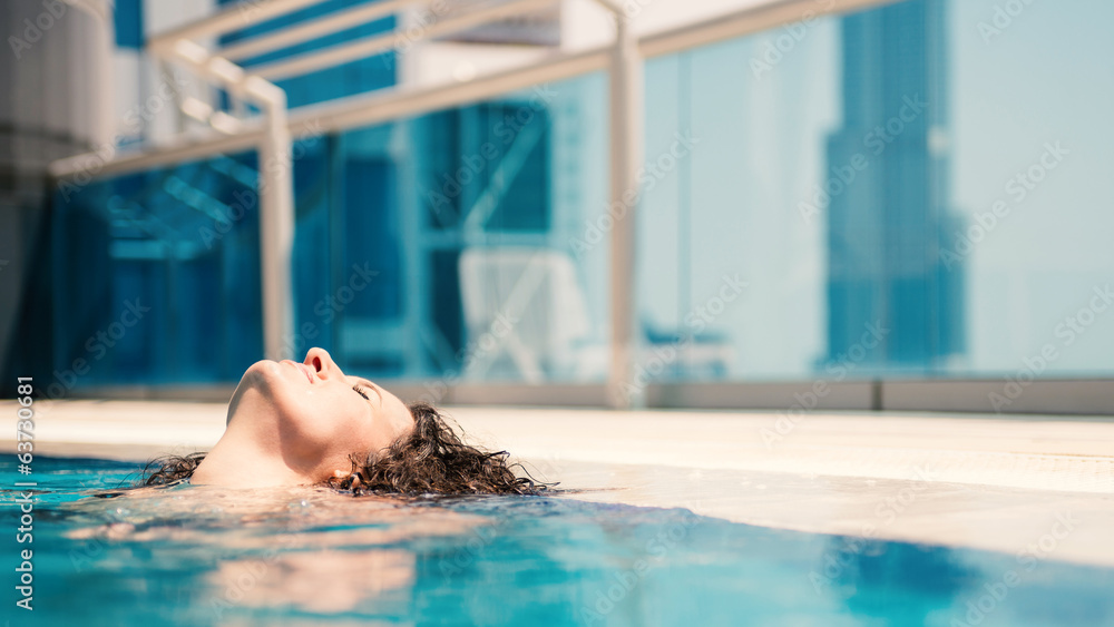 Young woman portrait wearing bikini sunbathing in swimming pool