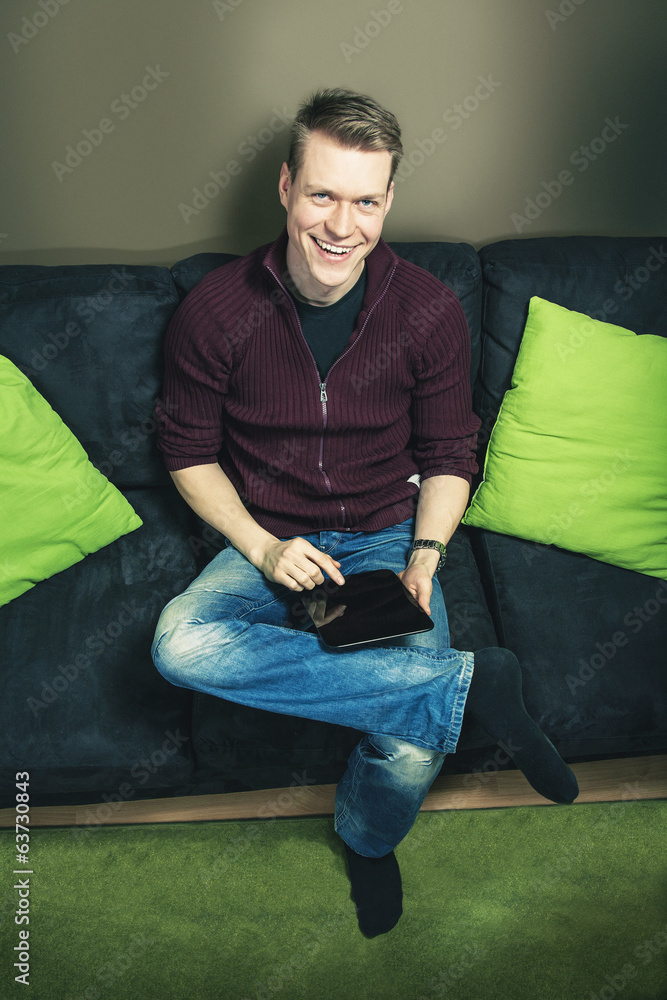 Man sitting on sofa using digital tablet looking up Man sitting on sofa using digital tablet looking up