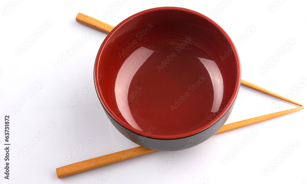 An empty bowl with a pair of chopsticks over white background An empty bowl with a pair of chopsticks over white background