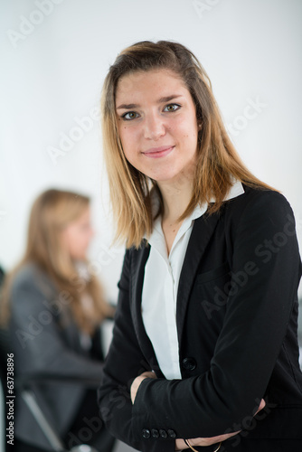 Cheerful young business woman standing up in the office