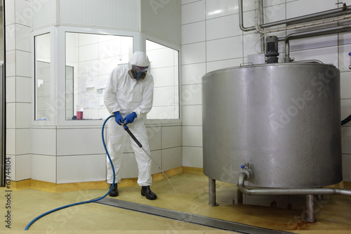 worker ,high pressure washer,  cleaning floor in plant photo