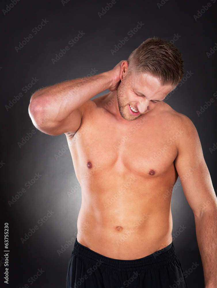 Obraz premium Fit muscular man massaging his neck in pain