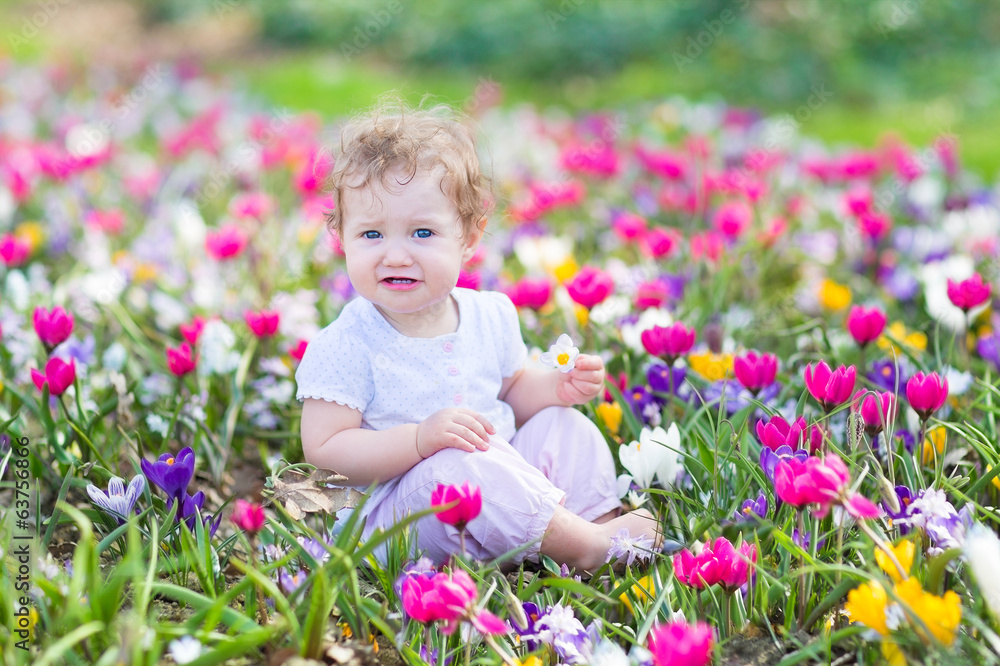 Funny laughing baby playing with first spring flowers Funny laughing baby playing with first spring flowers
