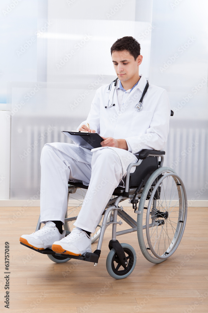 Doctor Witting On Clipboard While Sitting On Wheelchair Doctor Witting On Clipboard While Sitting On Wheelchair