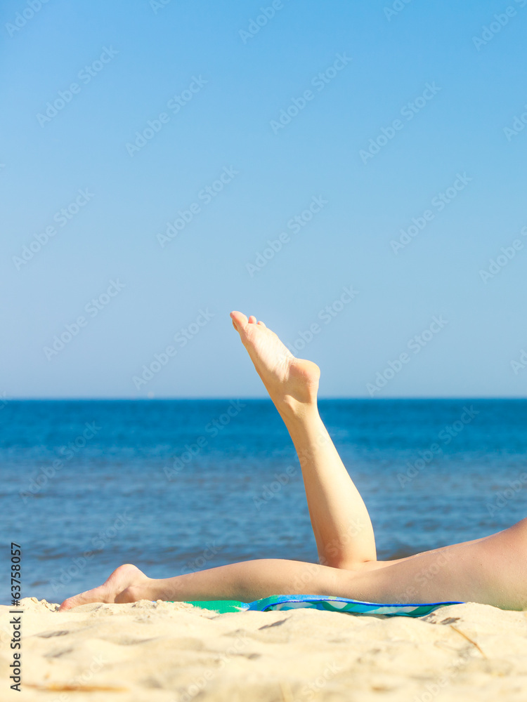 Summer vacation. Legs of sunbathing girl on beach Summer vacation. Legs of sunbathing girl on beach