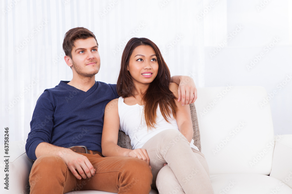 Smiling Young Couple Sitting On Sofa Smiling Young Couple Sitting On Sofa