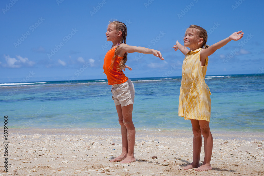 happy little girls standing at the beach in the day time