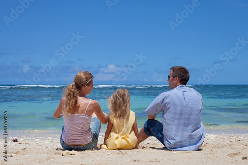 Happy family sitting on the beach in the day time