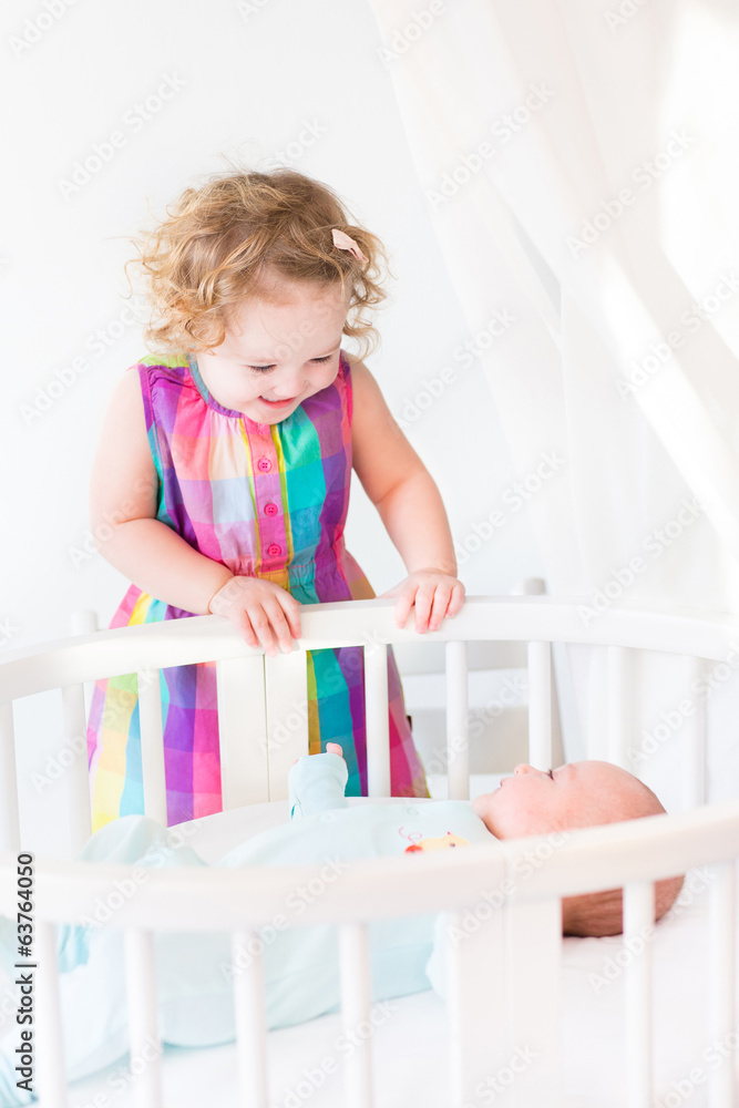 Cute newborn baby boy looking at his toddler sister Cute newborn baby boy looking at his toddler sister