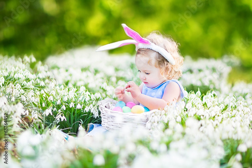 Adorable toddler girl wearing bunny ears with Easter eggs