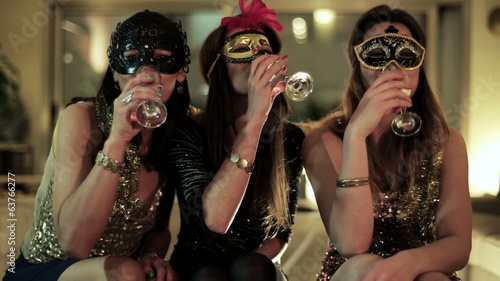 attractive women in masks making toast with glasses of champagne