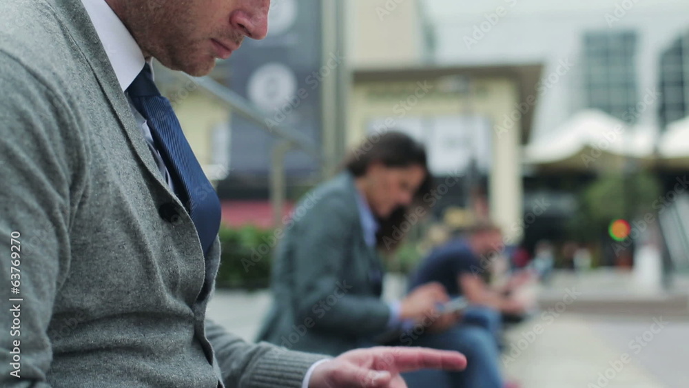 Businessman touching screen on tablet and sitting on street benc Businessman touching screen on tablet and sitting on street benc