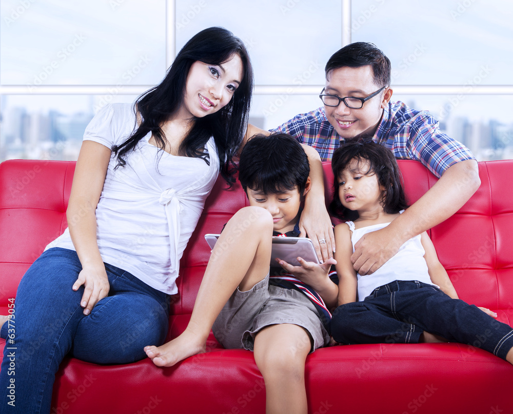 Happy family relaxing on red sofa at apartment Happy family relaxing on red sofa at apartment