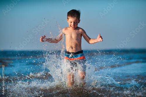 Little boy running through water at the beach © levranii