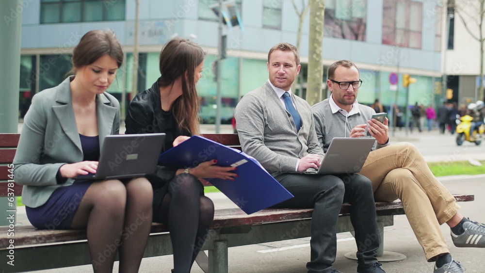 Businesspeople working on laptop and chatting in street bench Businesspeople working on laptop and chatting in street bench