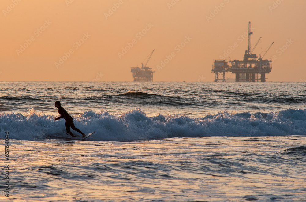 Fototapeta premium surfing on huntington beach with oil rigs in background