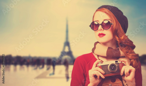 Redhead girl with camera on Paris background. © Masson