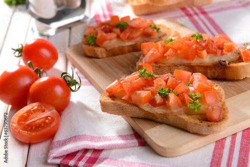 Delicious bruschetta with tomatoes on cutting board close-up